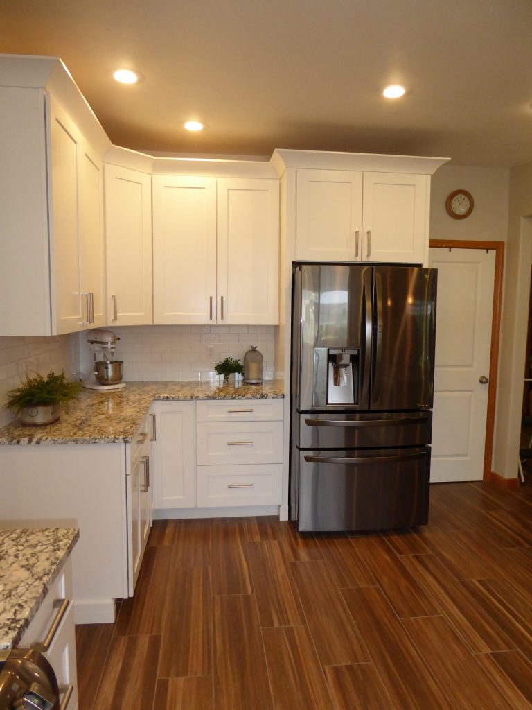 Remodeled kitchen with new refrigerator and wood-look tile floor